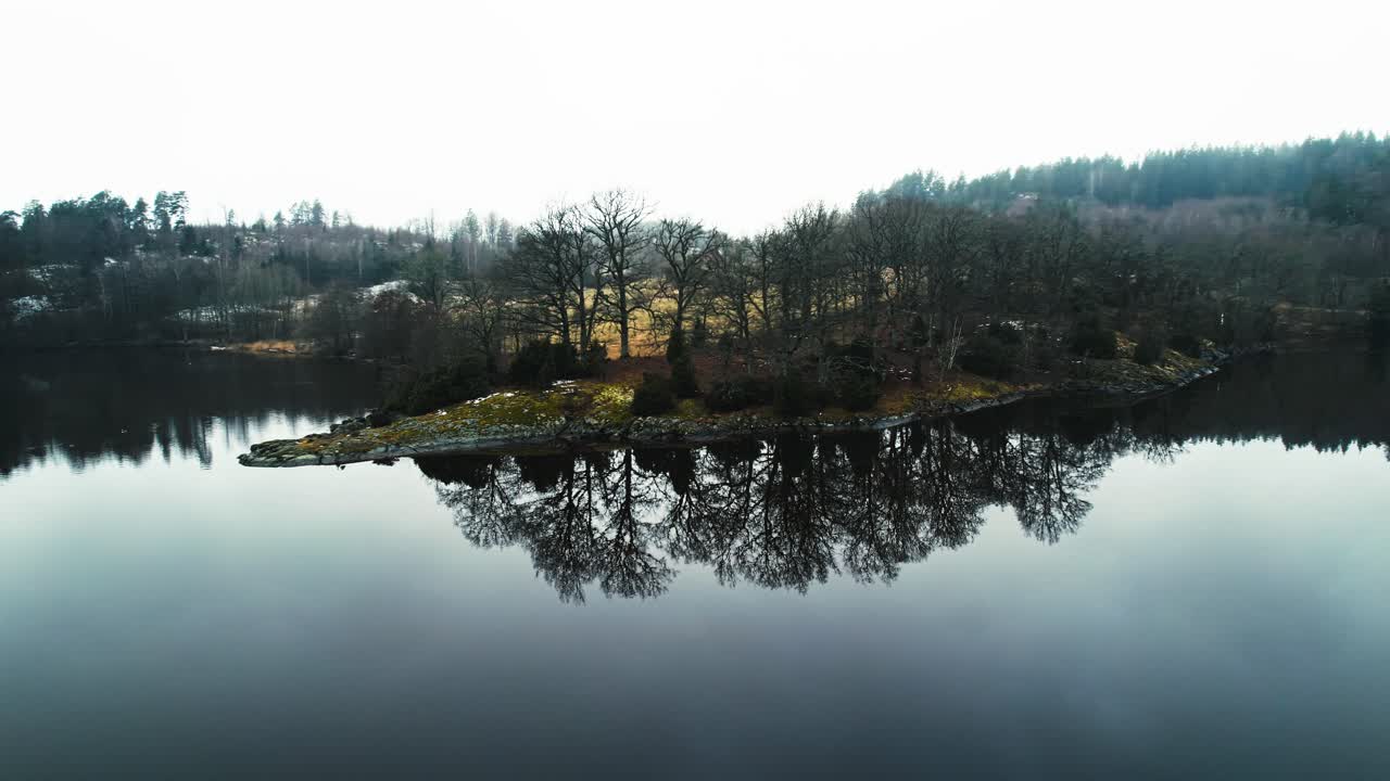 Tranquil island on calm lake reflecting serene atmosphere, Aerial parallax