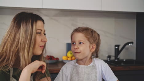 madre feliz y hija pequeña comen piezas de verduras