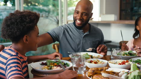 close up of family sitting around table at home enjoying meal together