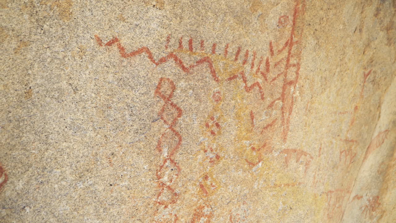 Primo piano di pittogrammi rossi dipinti sulla roccia.