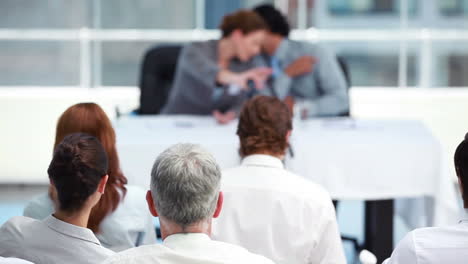 Man-whispering-something-to-his-colleague