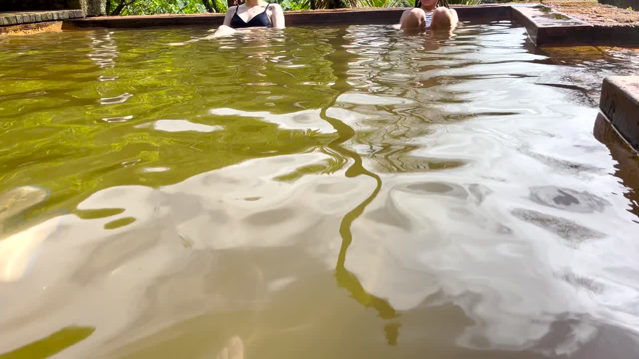 Close-up of thermal water in a pool with people relaxing. Daylight