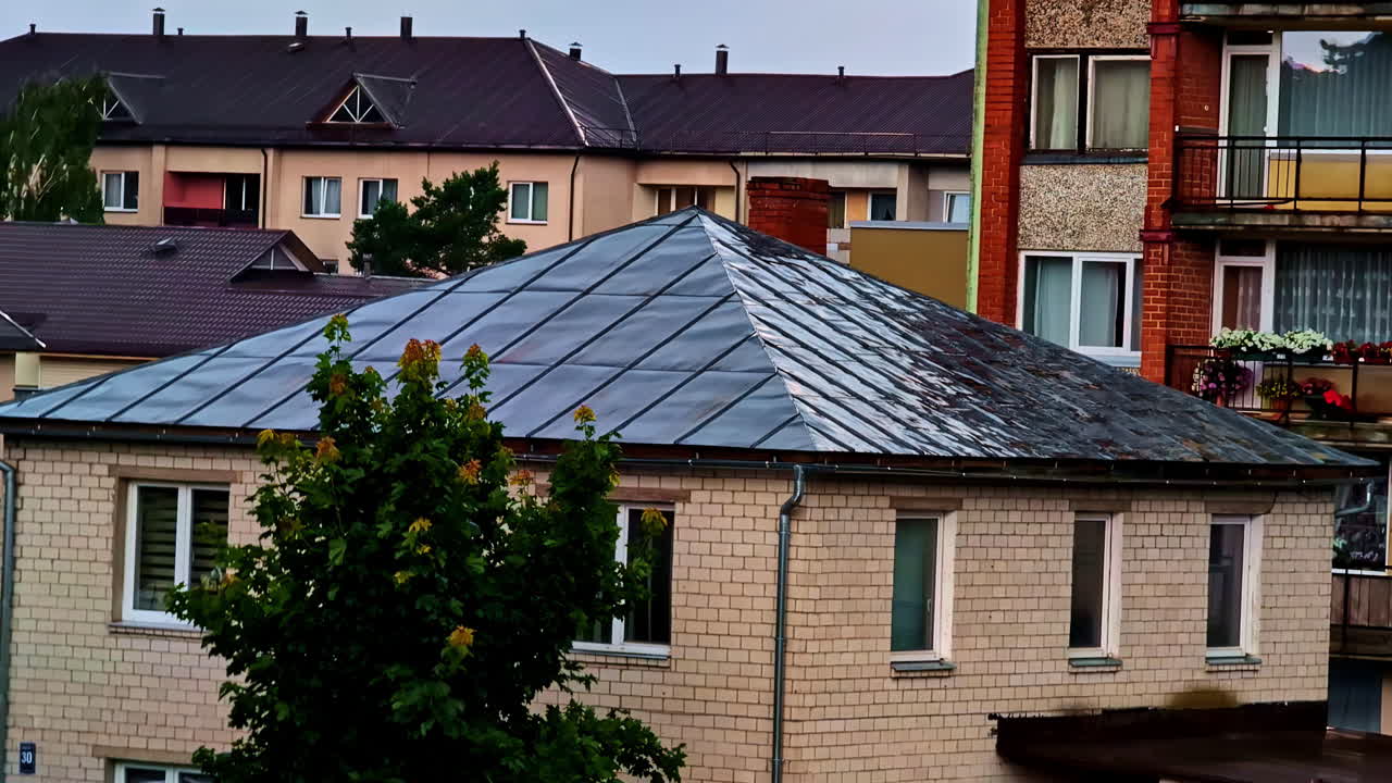 Brick House With Metal Roof Surrounded By Apartments on Overcast Rainy Day