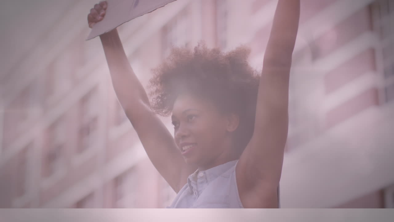 Animation of lights and lens flare over african american woman holding sign at protest in city