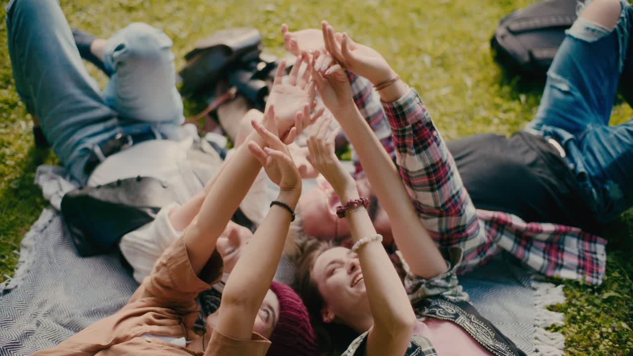 친구 들 이 공원 에 누워서 손 을 만지고 있다