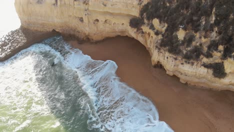 golden beach and rock outcroppings in carvoeiro, algarve, portugal - descent aerial shot