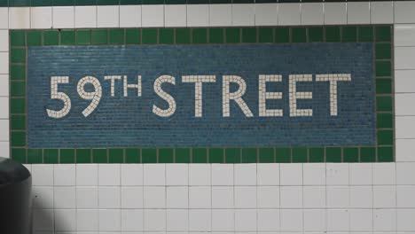 vibrant green, blue, and white tiles form a mosaic sign, marking the 59th street subway station