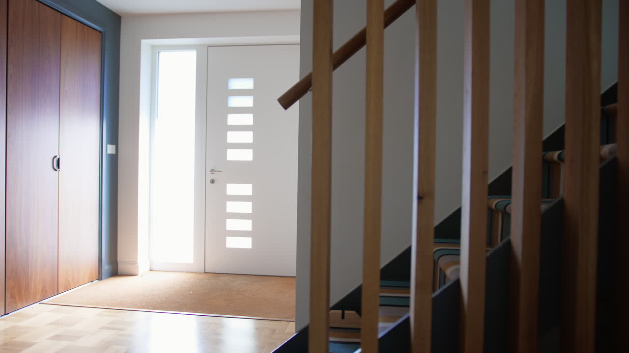 pasillo brillante y ligero con escaleras y puerta principal en una casa moderna