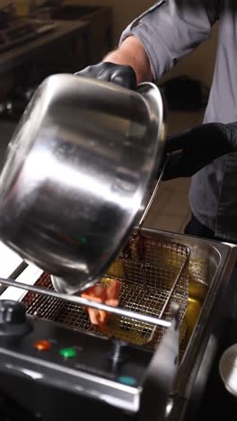 chef freyendo comida en una freidora profunda