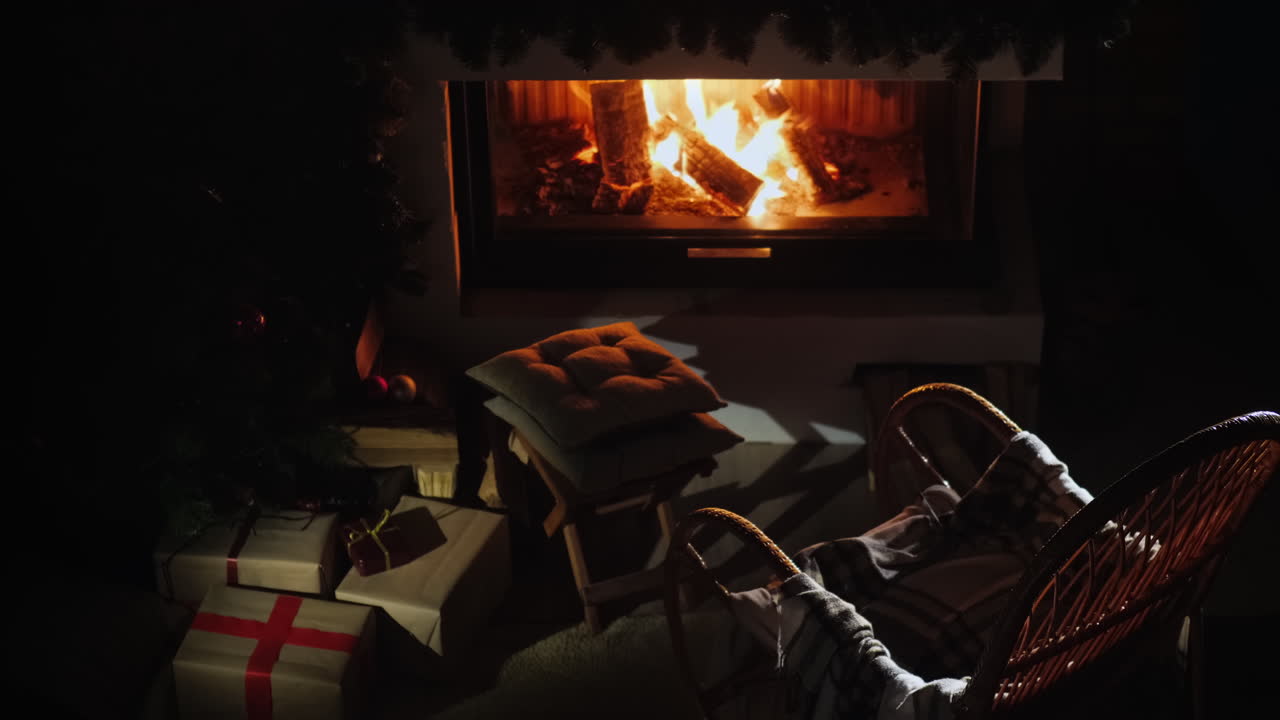 흔들의자는 겨울에 좋은 시간 동안 불꽃이 타오르는 벽난로 옆에 서 있습니다.