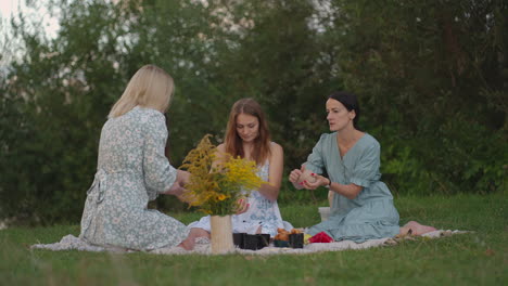 a group of young women are sculpting from clay listen to the master communicating in the field in the open air. the master explains the correct technique of sculpting. creative activities hobby.