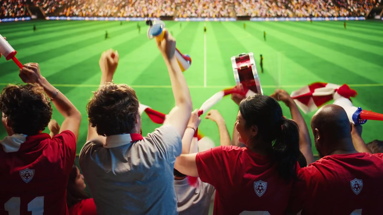 Tifosi appassionati guardano la partita di calcio, facendo il tifo e urlando.