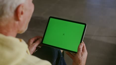un hombre hablando por video en una tableta con una pantalla verde en sus manos, copia el espacio