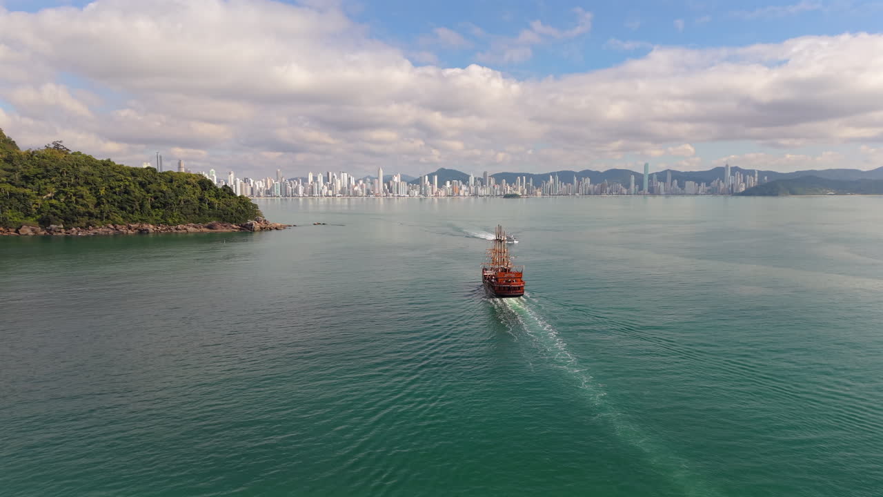A pirate ship sails across calm waters heading toward the coast of Balneario Camboriu