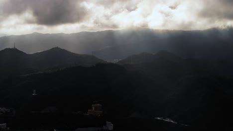 Dramatic-sunbeams-shining-through-stormy-clouds-timelapse-above-tropical-Kowloon-mountain-landscape