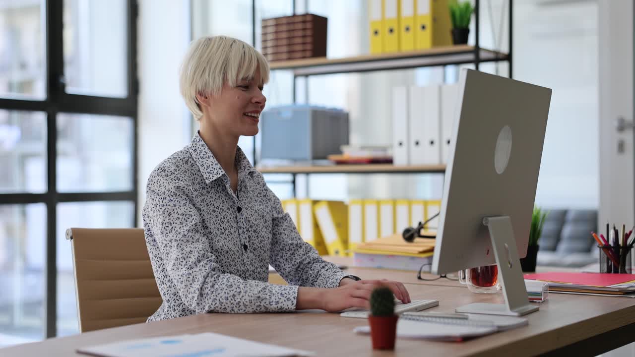 Happy lady worker types data to client on computer keyboard