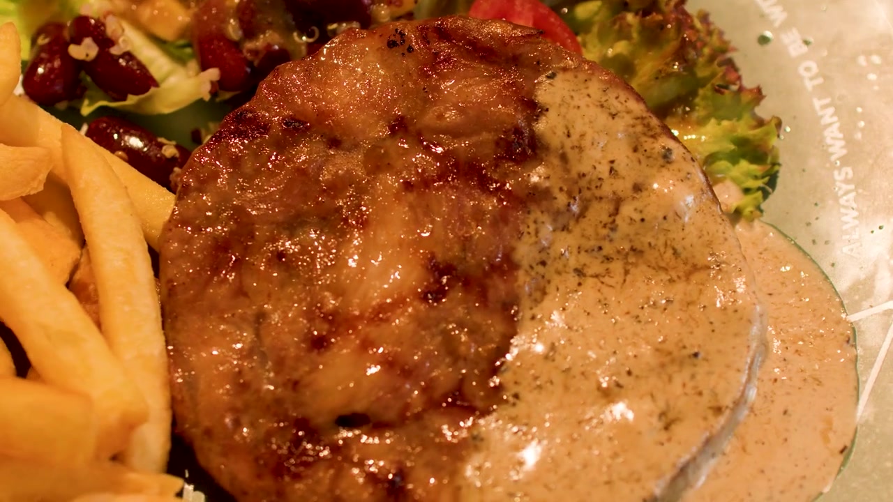 Primo piano di una bistecca alla griglia guarnita con salsa cremosa ai funghi e un'insalata fresca di contorno.