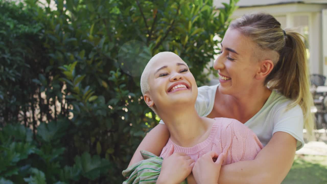 retrato de una feliz pareja de mujeres diversas abrazándose en un día soleado en el jardín