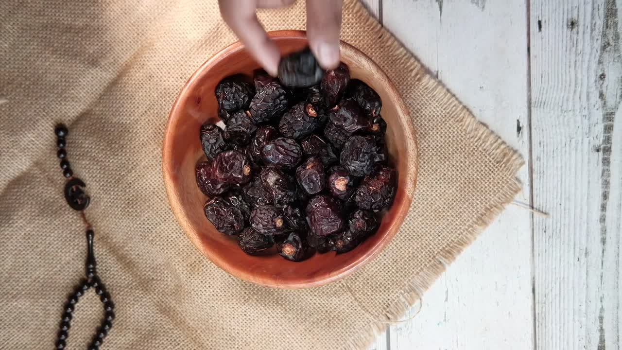Hand reaching into a bowl of dates