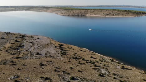 Aerial-view-on-a-small-white-boat-travelling-on-blue-waters-camera-is-moving-forward