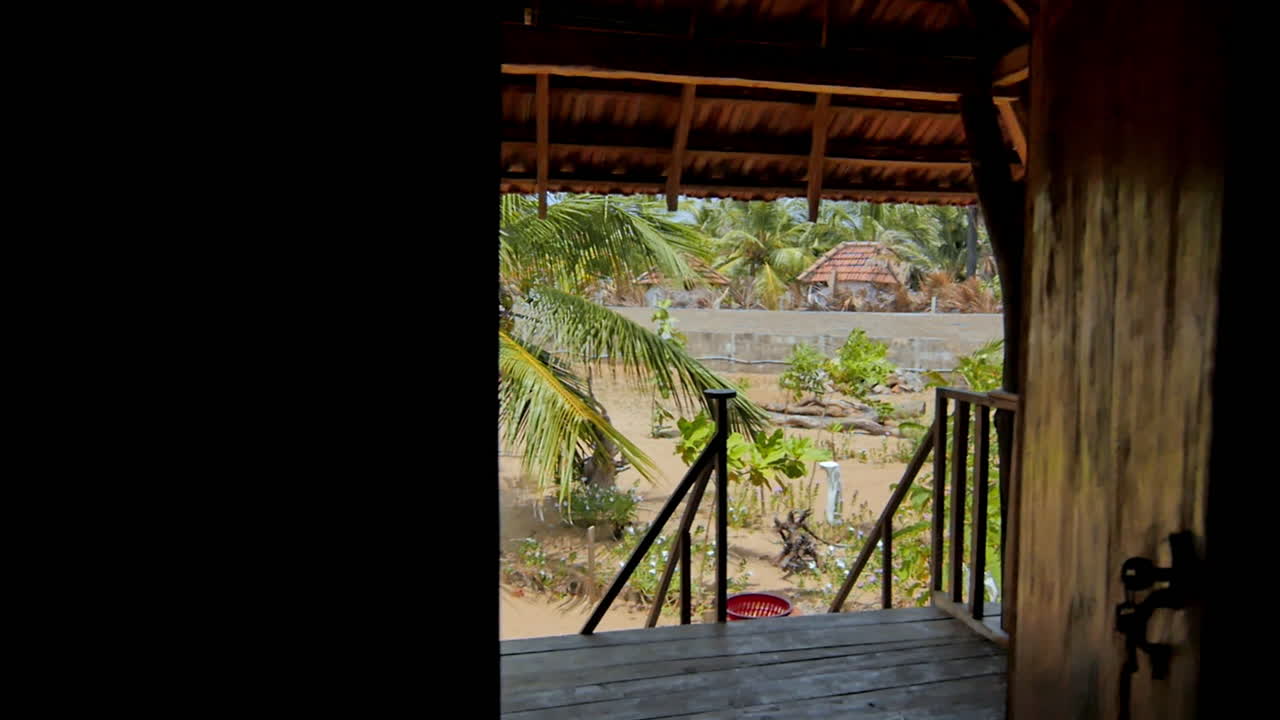 tranquil tropical scene seen through a wooden hut doorway, with palm trees and golden sand inviting the eye outside