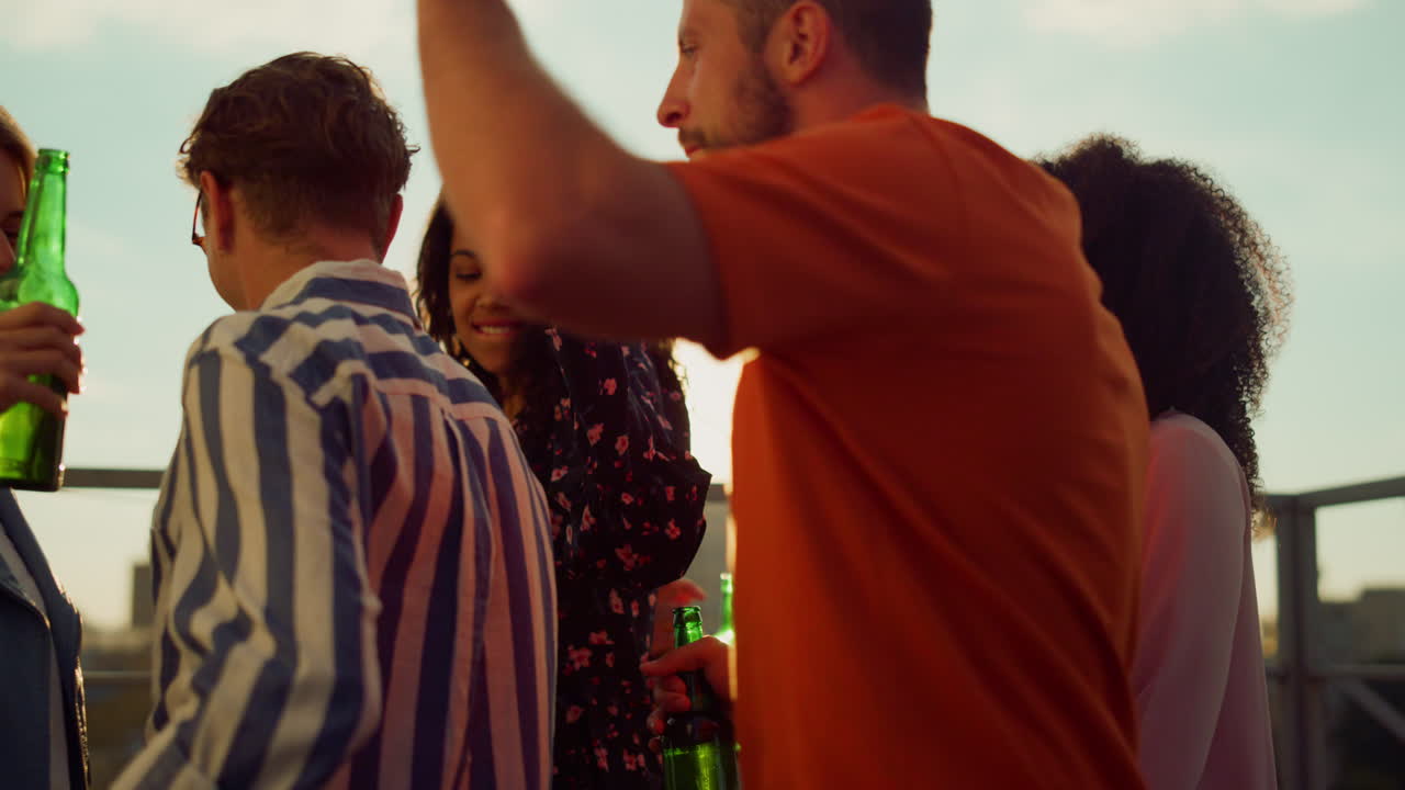 hermosos amigos de fiesta en la terraza. personas multiétnicas celebrando con cerveza