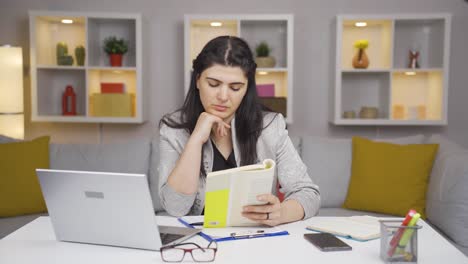 una trabajadora de oficina en casa leyendo un libro.