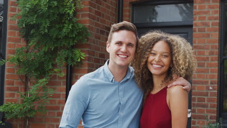 portrait of excited young couple standing outside new home together