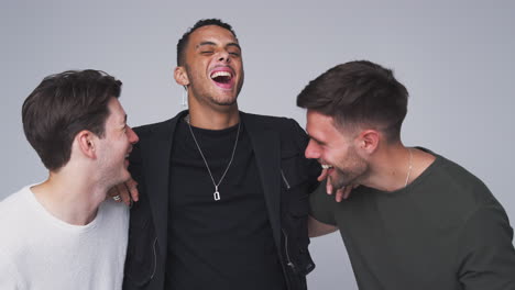 group studio portrait of multi-cultural male friends smiling into camera together in slow motion