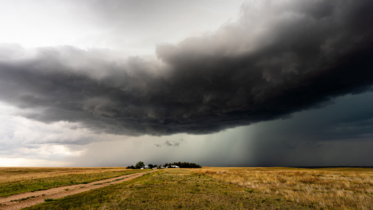 Dark powerful storm clouds move over a small farm time lapse
