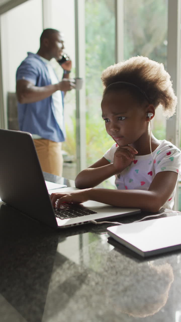 video vertical de padre e hija afroamericanos usando una computadora portátil