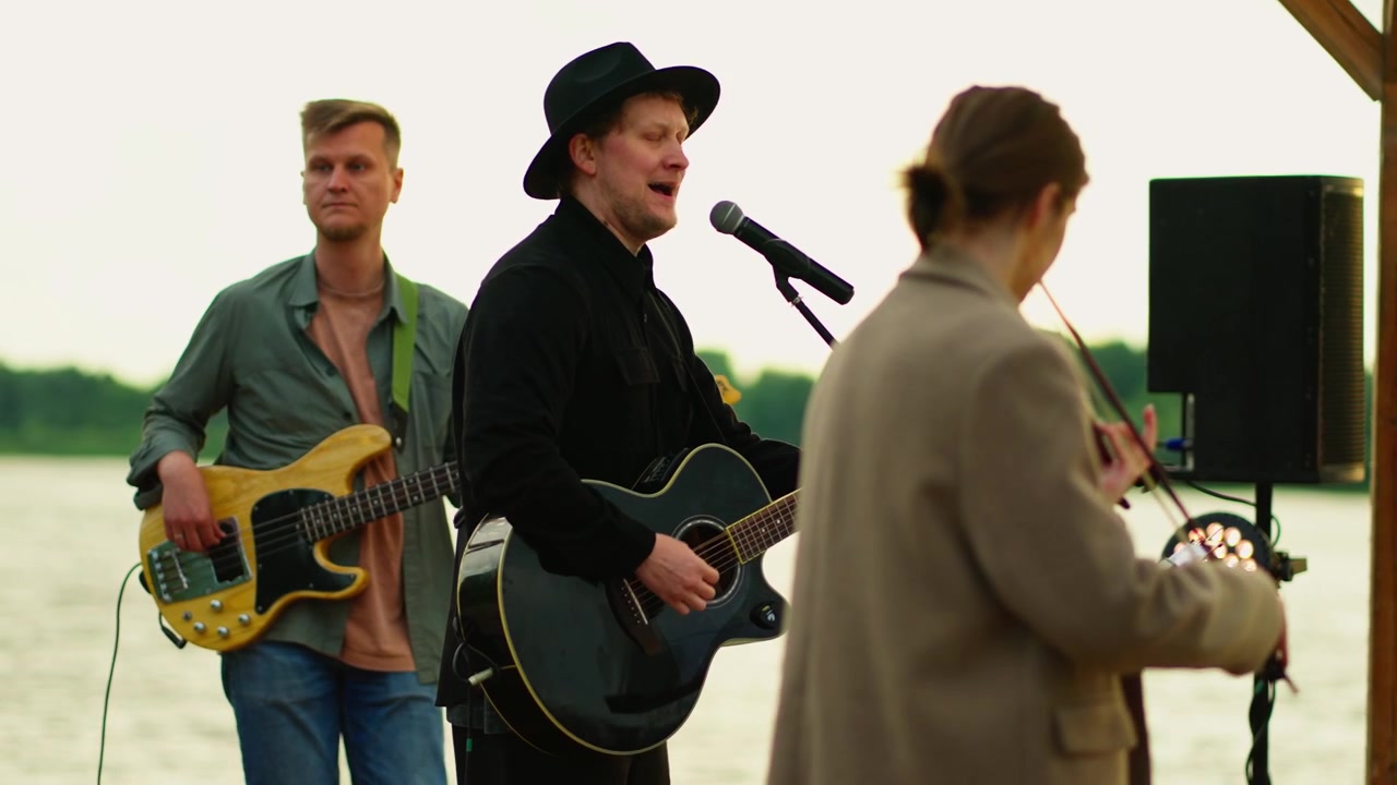 Musical Trio Performing Live Music Outdoors by the Lake