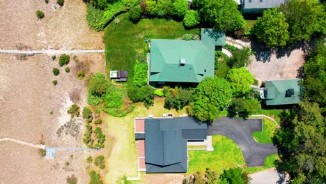 aerial drone footage showcases multiple cottage-style homes nestled in a serene suburban neighborhood, with large back porches, cozy patios, green lawns, and tall trees surrounding each property