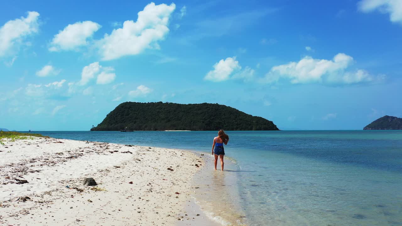 chica haciendo gimnasia en la tranquila costa de una isla tropical con guijarros blancos bañados por aguas tranquilas y claras al amanecer con un cielo azul brillante