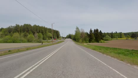 Die-Straße-Schlängelt-Sich-Durch-Eine-Malerische-Landschaft-Mit-üppigen-Grünen-Feldern-Und-Dichten-Wäldern,-Wobei-Lebhafte-Autos-Der-Malerischen-Aussicht-Farbtupfer-Verleihen