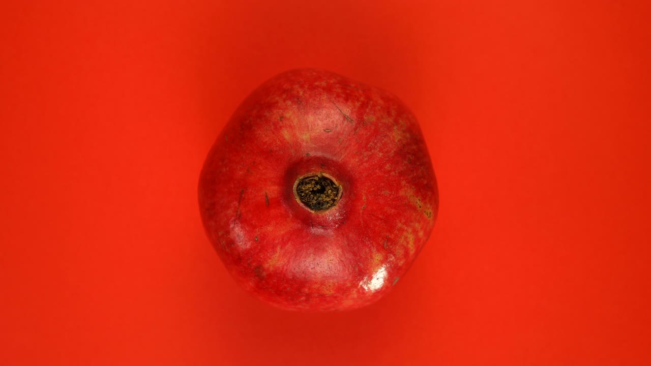 Modne hele granatæblefrugter roterer omkring deres akse på en rød baggrund