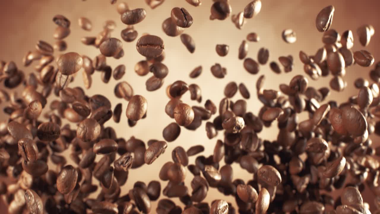 Chicchi di caffè profumati si librano nell'inquadratura. Chicchi di caffè ripresi con una telecamera super slow motion a 1000 fps.