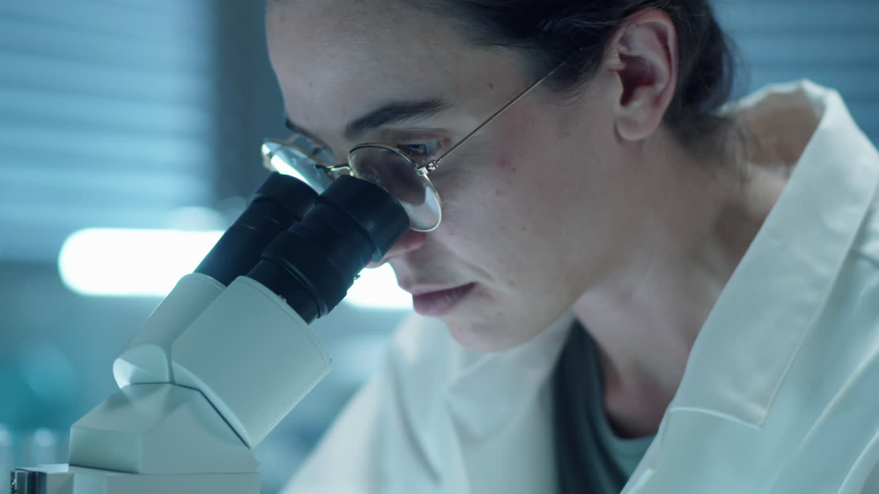 Scienziata che osserva al microscopio in laboratorio
