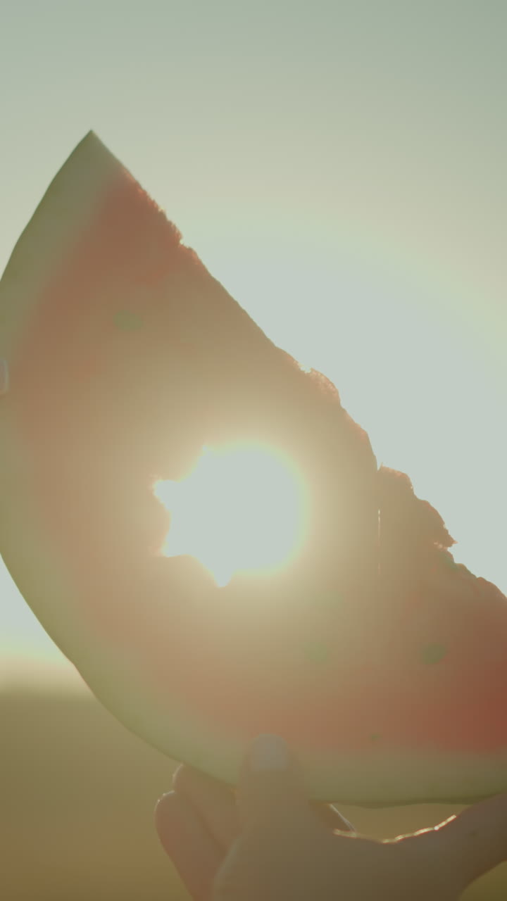 빛이 빛나면서 아름다운 빛 효과와 반이는 실루을 만드는 별의 절단 모양의 수박 조각을 들고 있는 여성의 클로즈업