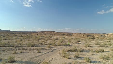 aerial footage of a group of bicycle riders riding on bike trails in the desert