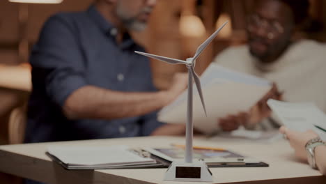 wind turbine model on office table during team meeting of engineers