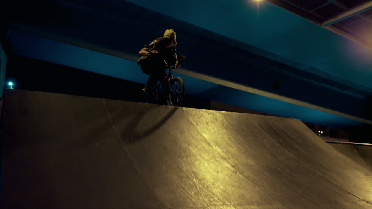 Extreme man riding bmx bike at night in urban skatepark. Bmx rider practicing.