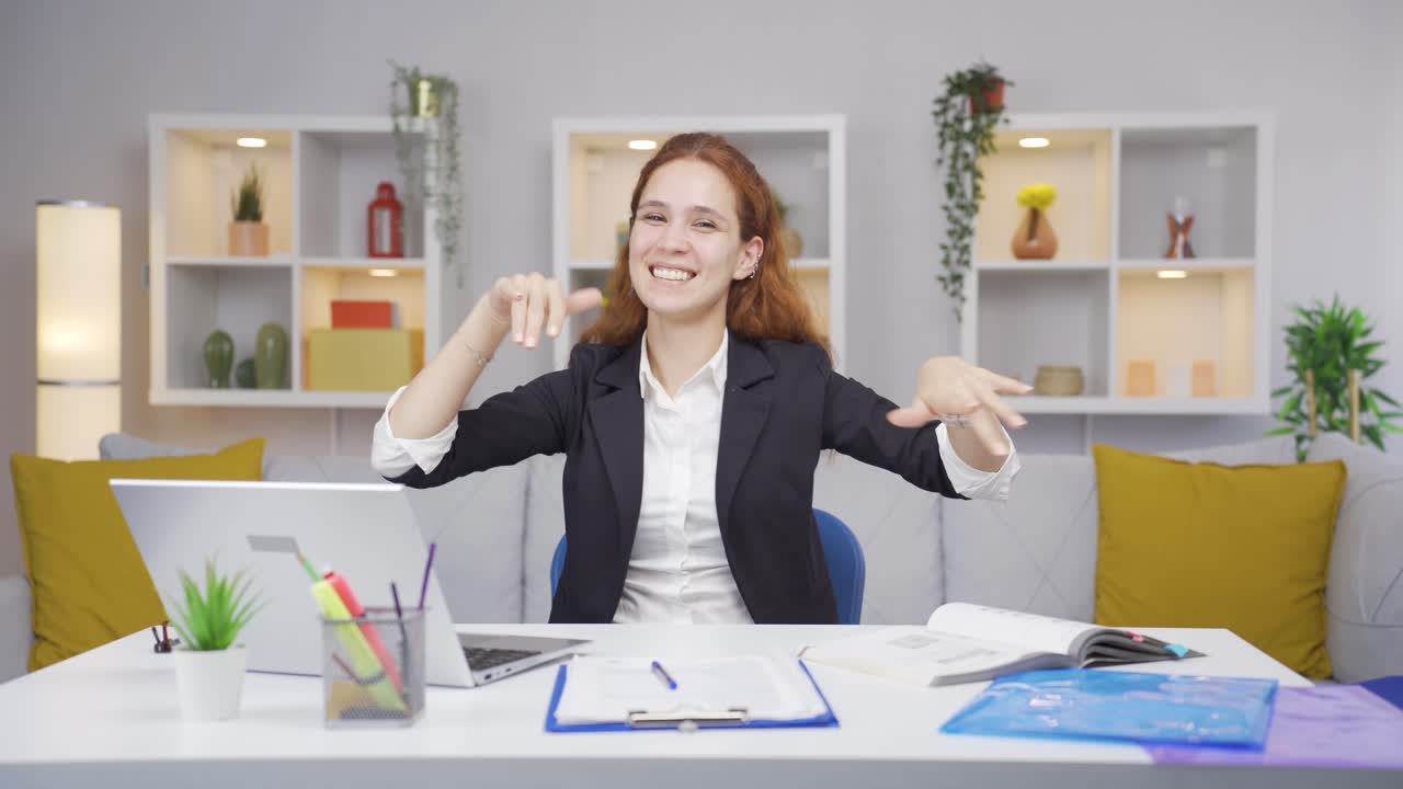 Home office worker woman dances looking at camera.