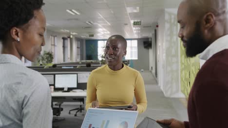 happy african american male and female business colleagues discussing in office, slow motion