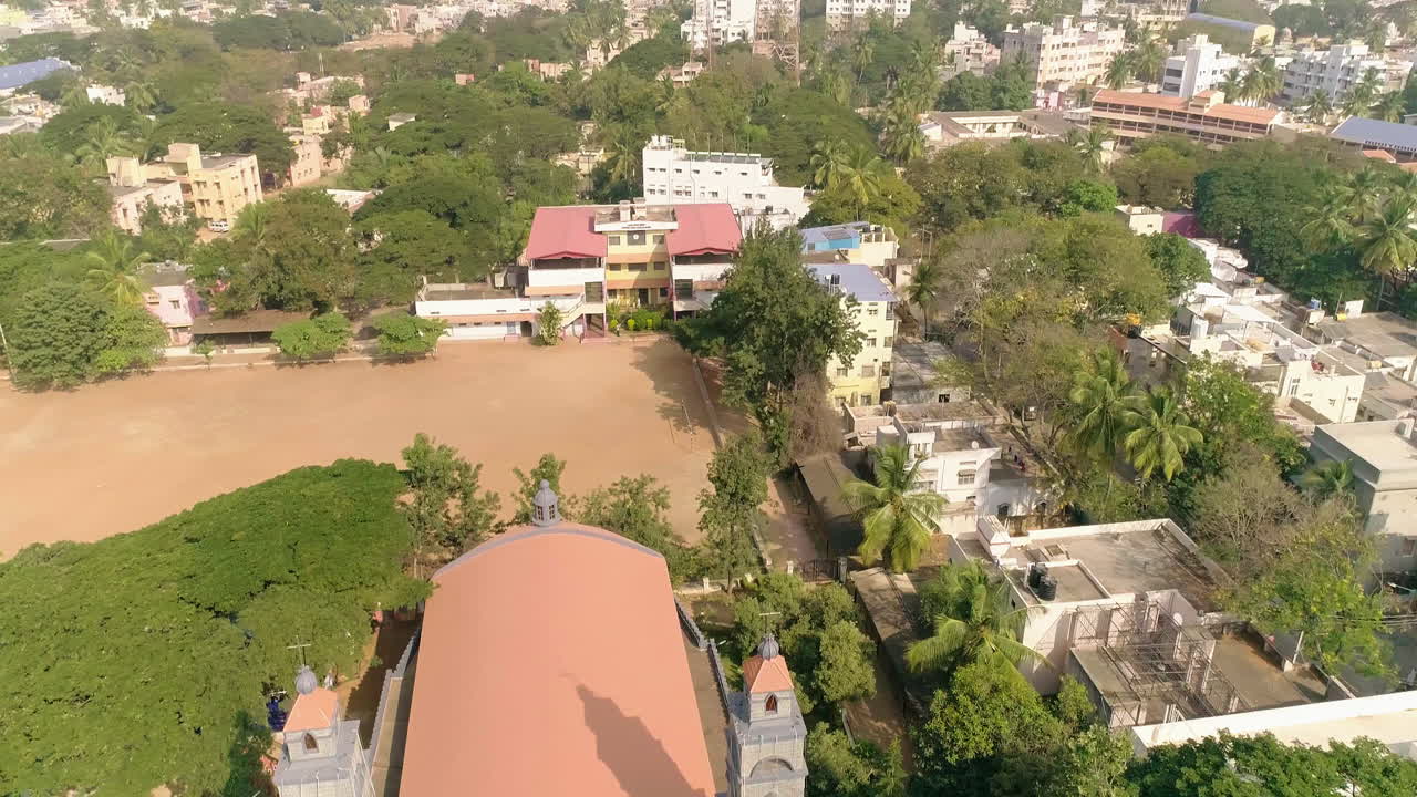 Pan across Davanagere city, Karnataka India, with trees, buildings and church on a sunny day, aerial view
