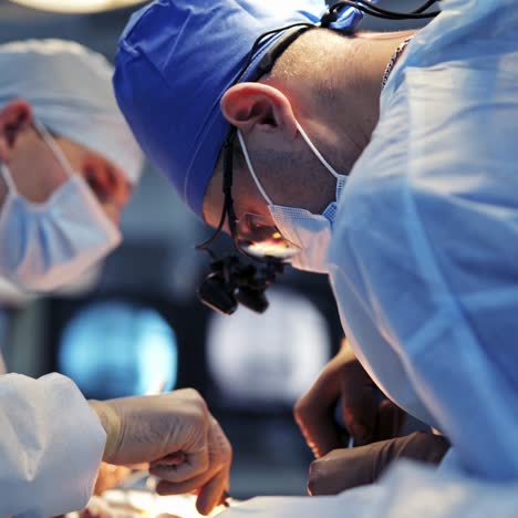 neurosurgeons in face masks and surgery glasses operate patient with special instruments. medics in scrubs shoot under selective angle
