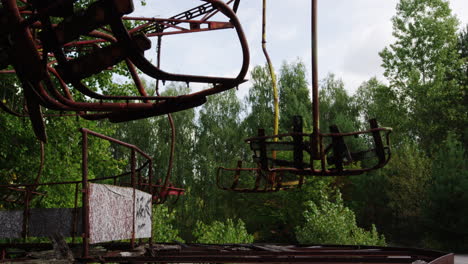 rusty amusement park swing ride in pripyat, low angle zoom out view