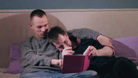 two men reading together in bed