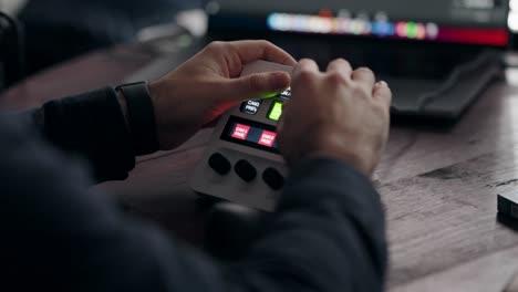 hands operating an electronic device with buttons on a wooden desk