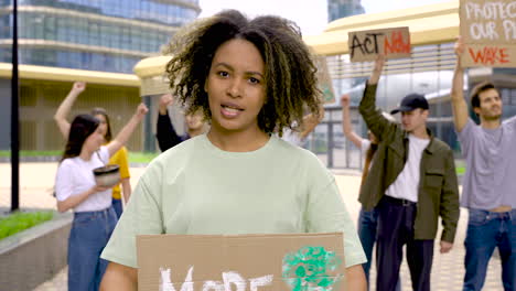 Woman-Holding-More-Trees-Less-Lies-Placard-On-A-Protest-With-More-Colleagues